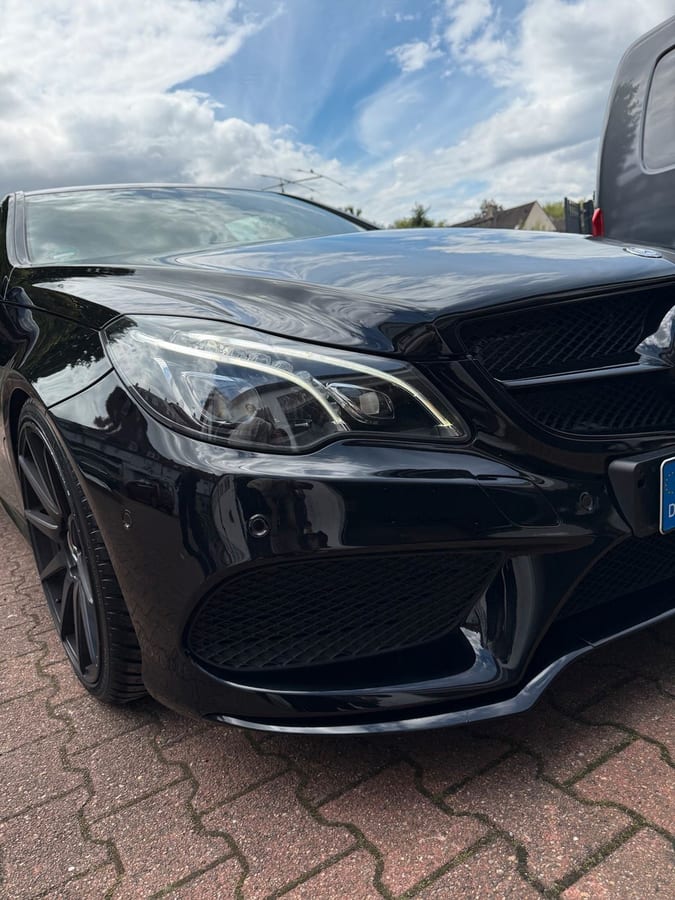Motorhaube eines schwarzen Mercedes, in der sich nach der Politur der Himmel spiegelt